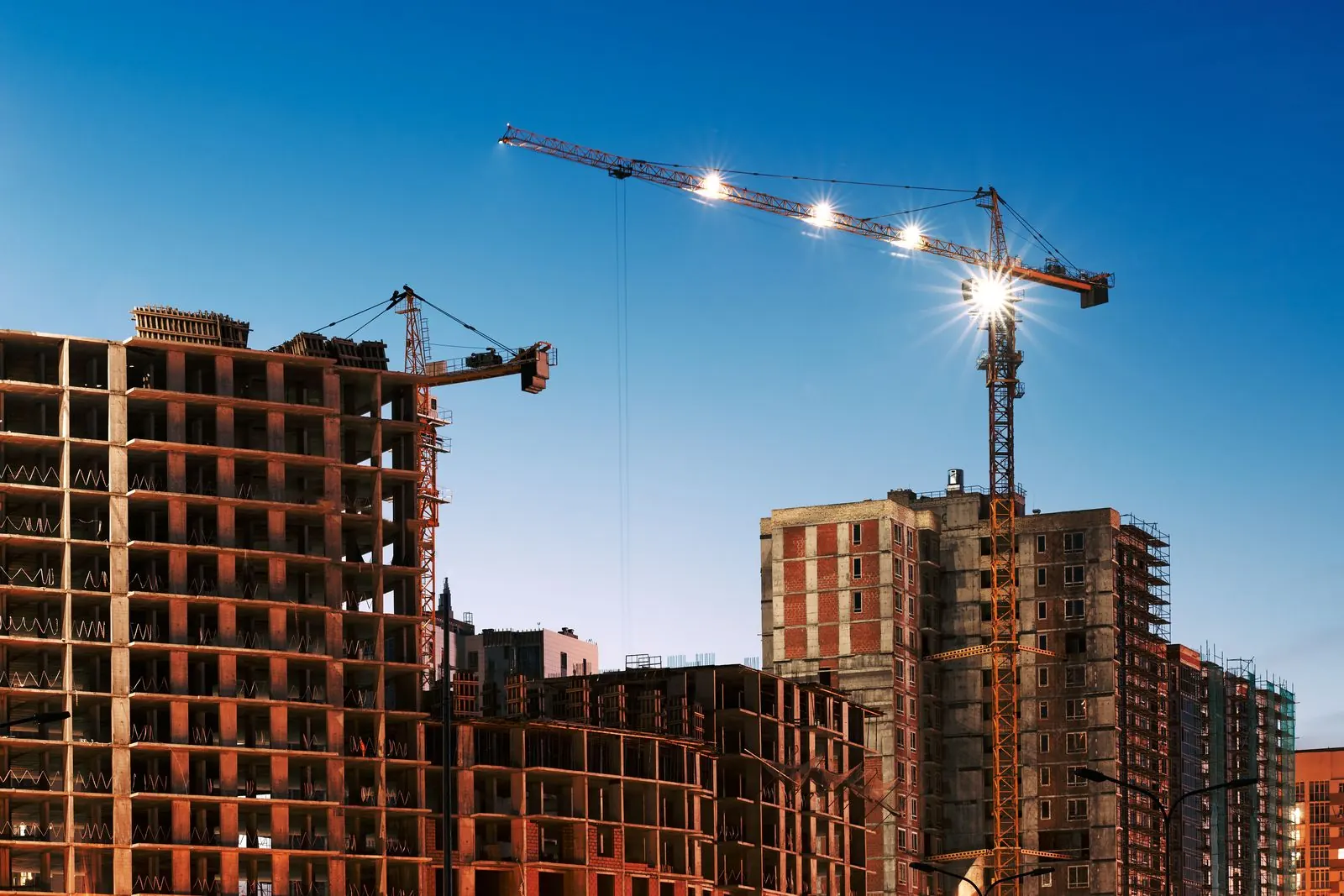 Mid-rise commercial construction cranes at blue hour